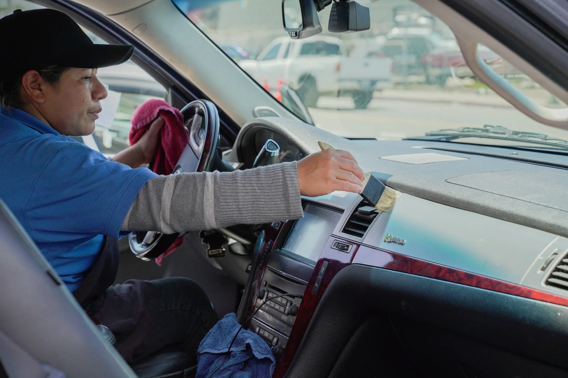 Detailer brushing dust from interior dashboard vents